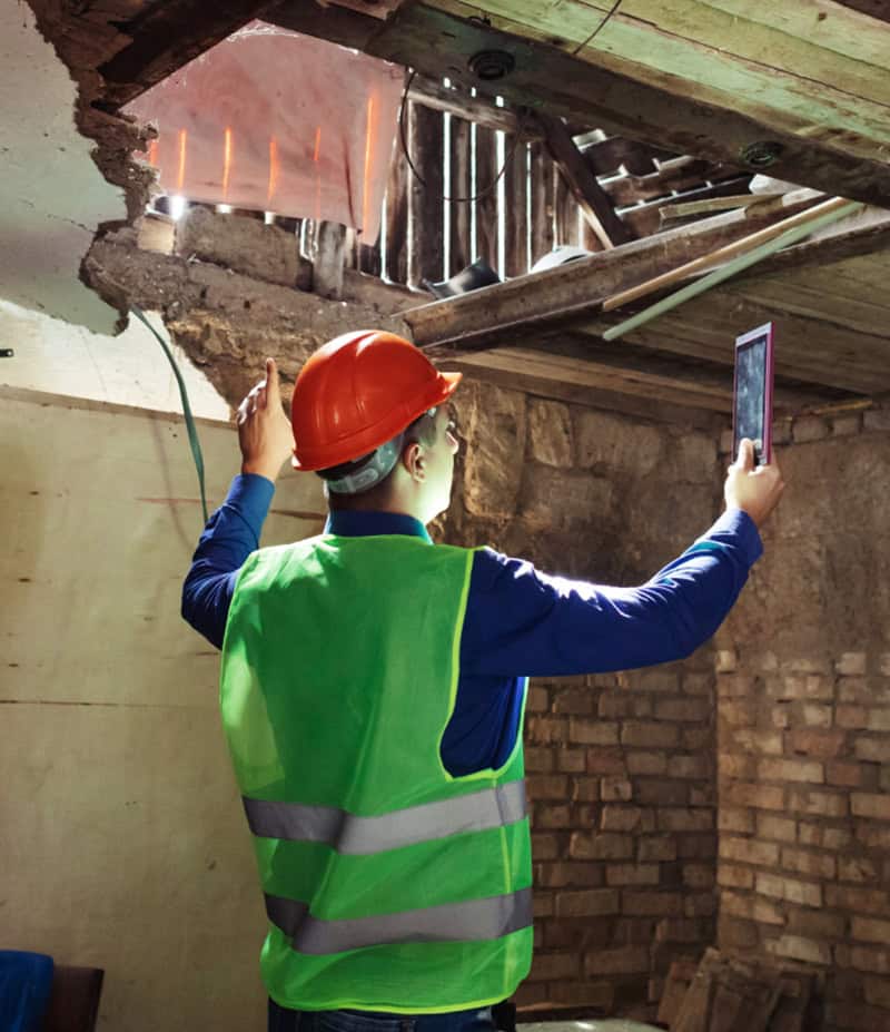 Worker inspecting damages roof