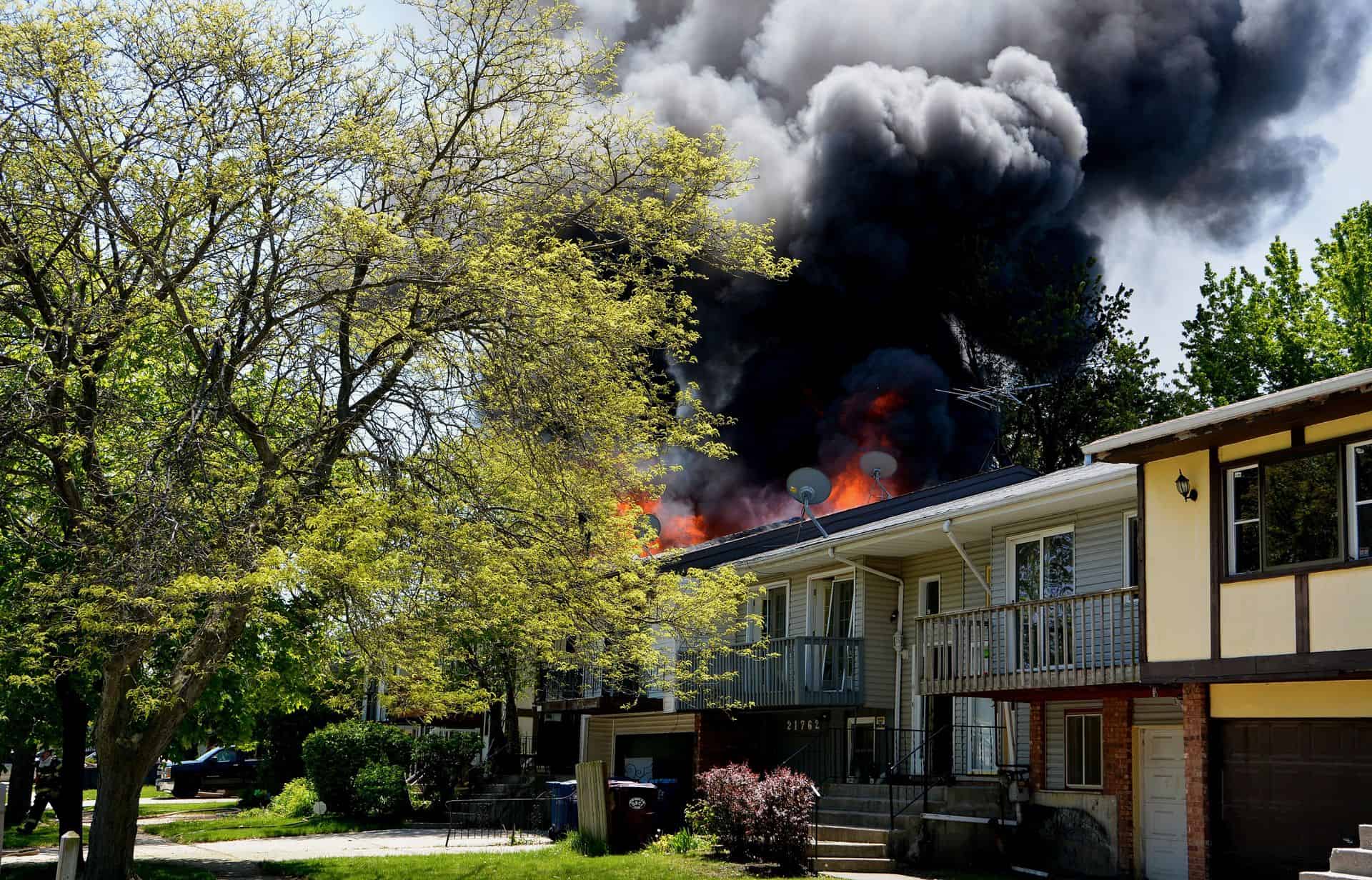 orange flames and dark smoke coming from a home during a house fire.
