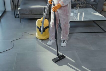 a cleaning professional using a HEPA vacuum on a stone floor.
